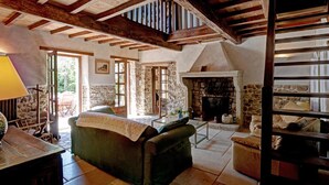 Un interior rústico con vigas de madera a la vista, una chimenea de piedra y una zona de estar acogedora.