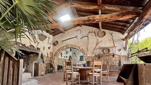 Un interior rústico de piedra con chimenea de piedra, muebles de madera y un arco de piedra.