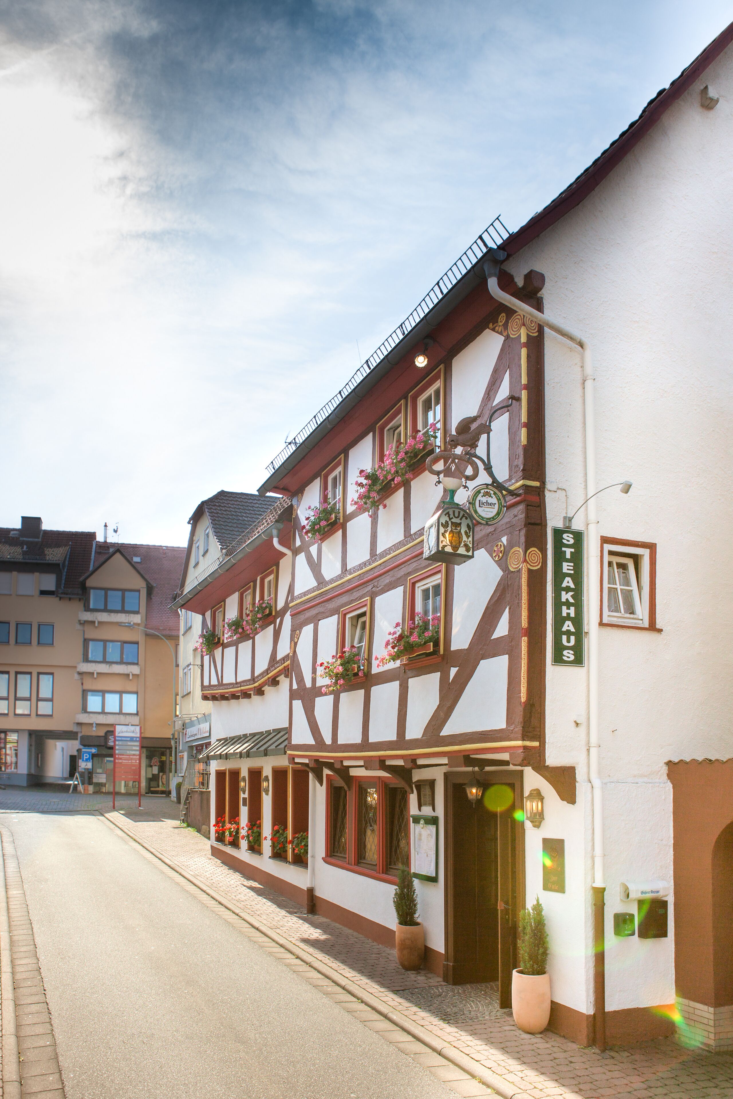 A traditional half-timbered building with a sign reading "STEAKHAUS" and flower boxes on the windows.