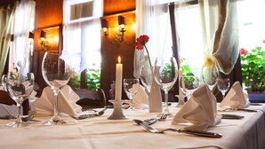 A table set for dining with wine glasses, a candle, and a vase with a flower. - Pension EulenNest (Laubach)