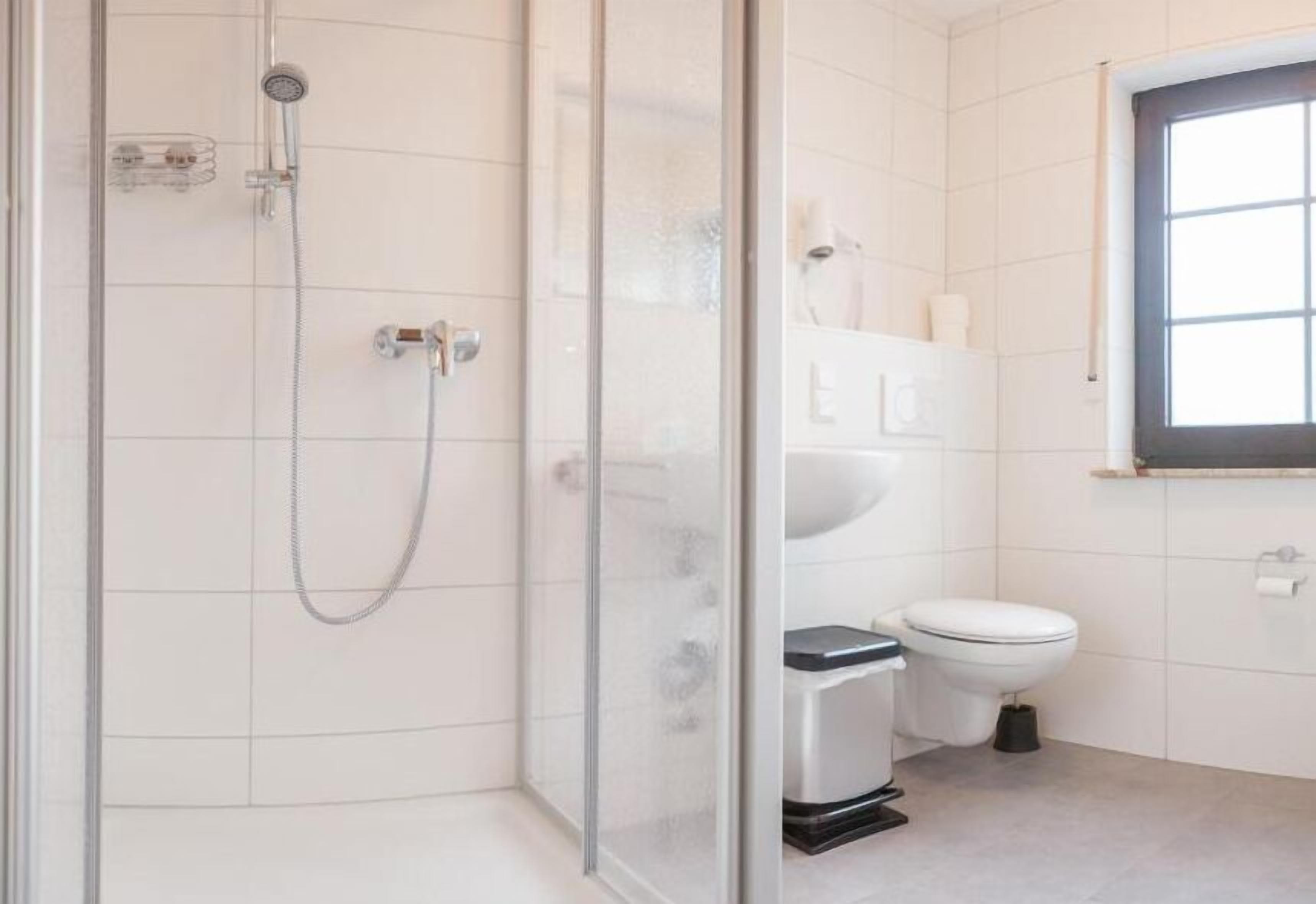 Un baño moderno con ducha de vidrio, inodoro blanco y lavabo.