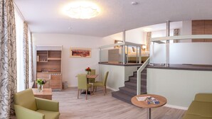A modern hotel room with a dining area, a staircase, and a view of the city. - Pension EulenNest (Laubach)
