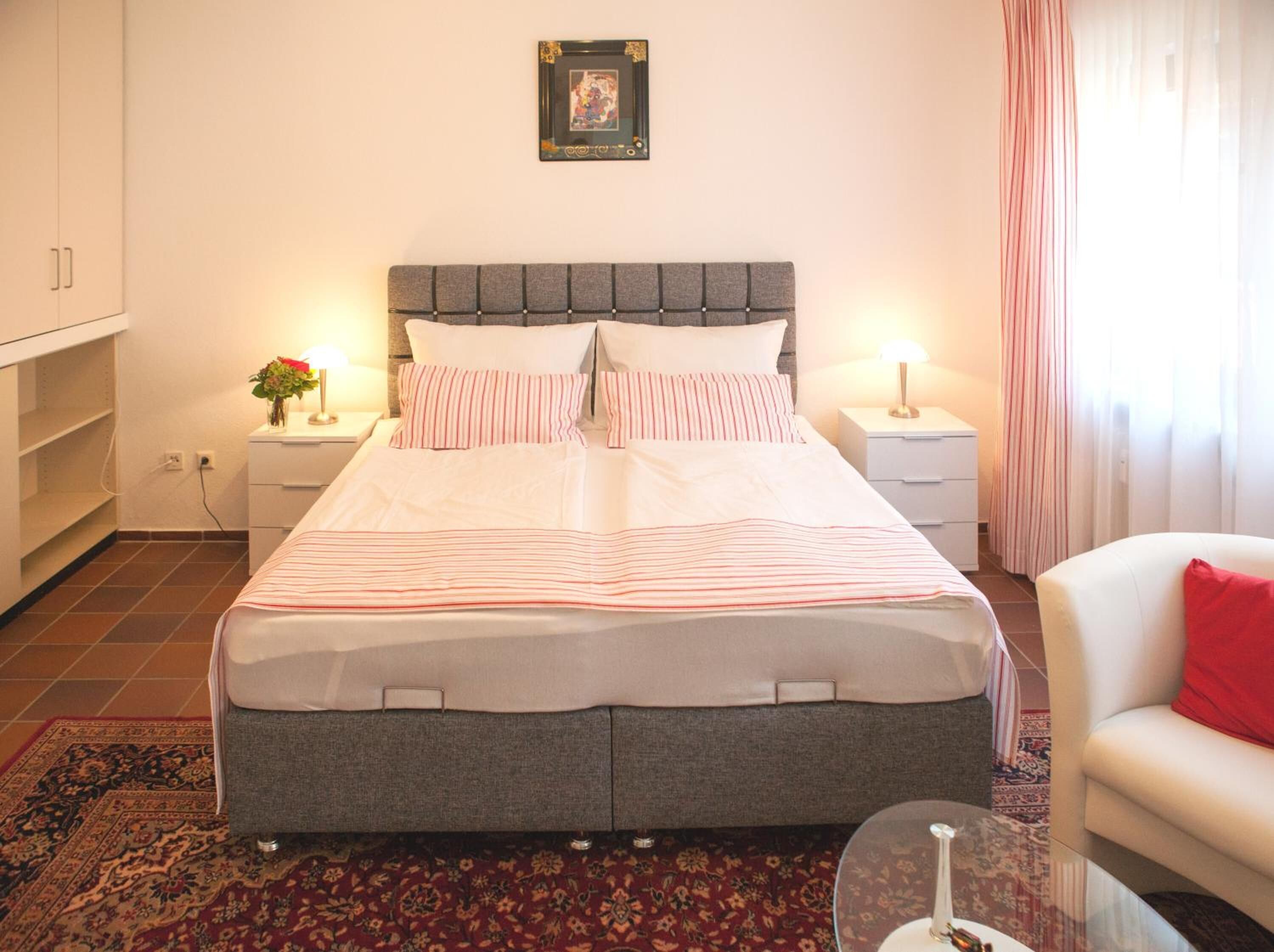 Une chambre bien rangée, avec un lit, des tables de chevet, une chaise et un tapis.