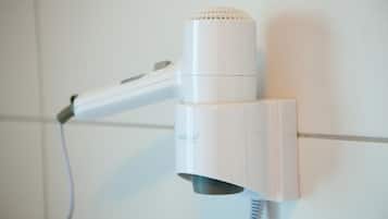 A white hair dryer mounted on a wall with a cord.
