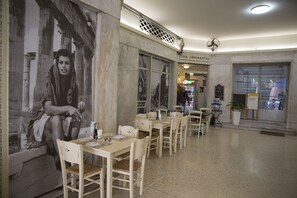 A restaurant with white tables and chairs, a large mural on the wall, and a sign for 'STOA SEMPORITOS'. - Super Stylish Apartments in Syntagma Square (Athens)