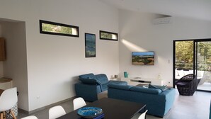A modern living room with a dining area, featuring a sofa set, a dining table with chairs, and a flat-screen TV mounted on the wall. - Exceptional Villa with Ocean Views in Campomoro, Sleeps 6, Near the Beach (BELVEDERE-CAMPOMORO)
