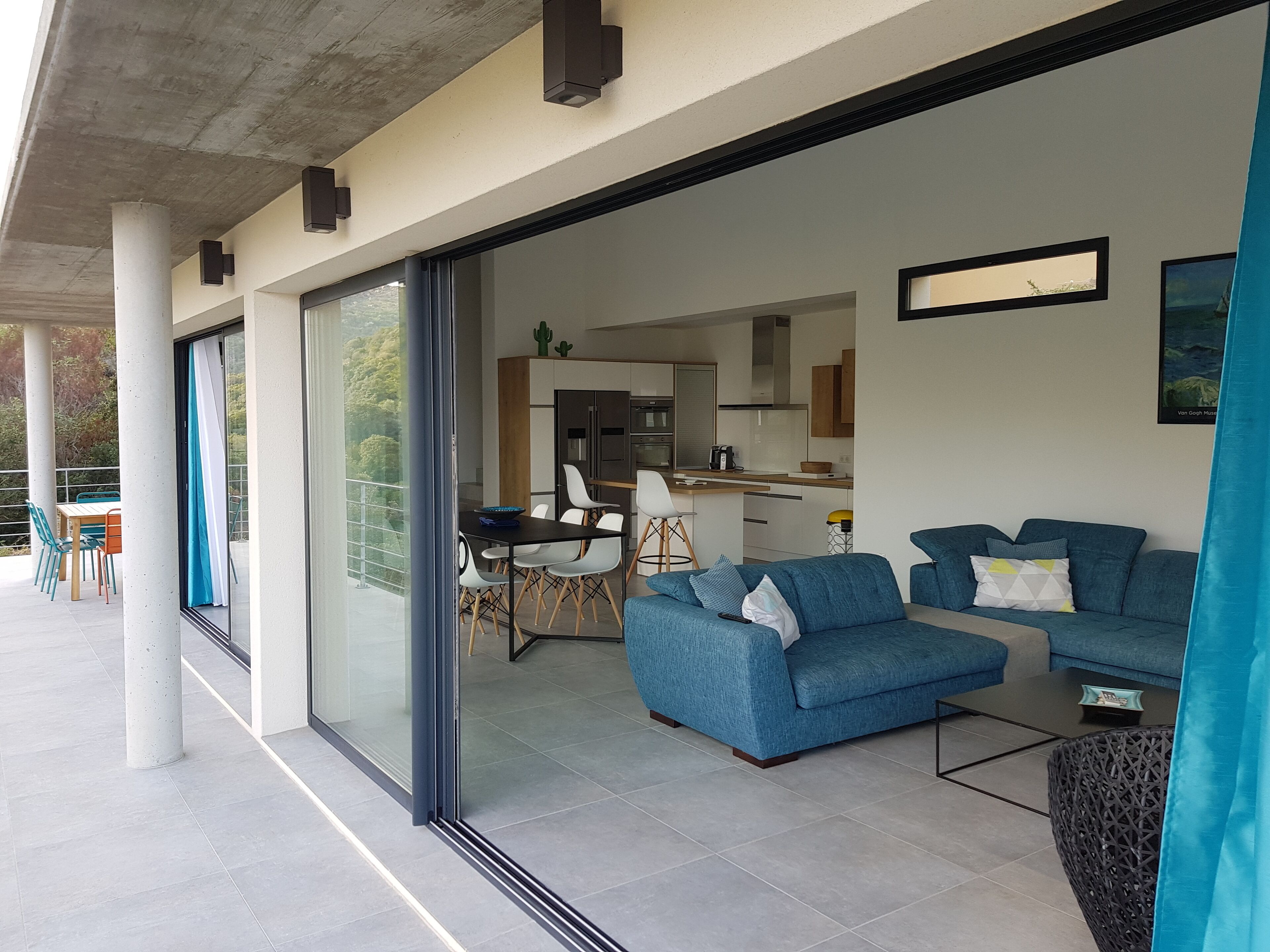 A modern living space with a dining area, a kitchen, and a balcony with outdoor seating.