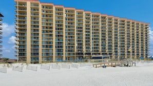 A high-rise hotel with multiple balconies and a beach view. - Beachfront 2BR @ Phoenix V • Sleeps 8 • Balcony Views, Pools, Indoor Pool & Pirate Splash Pad (Orange Beach)