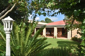 A building with a red roof, surrounded by lush greenery and a well-maintained lawn. - Siesta B&B (Abaqulusi)