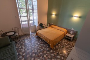 Una habitación de hotel con cama, una mesita, una silla y un sofá.