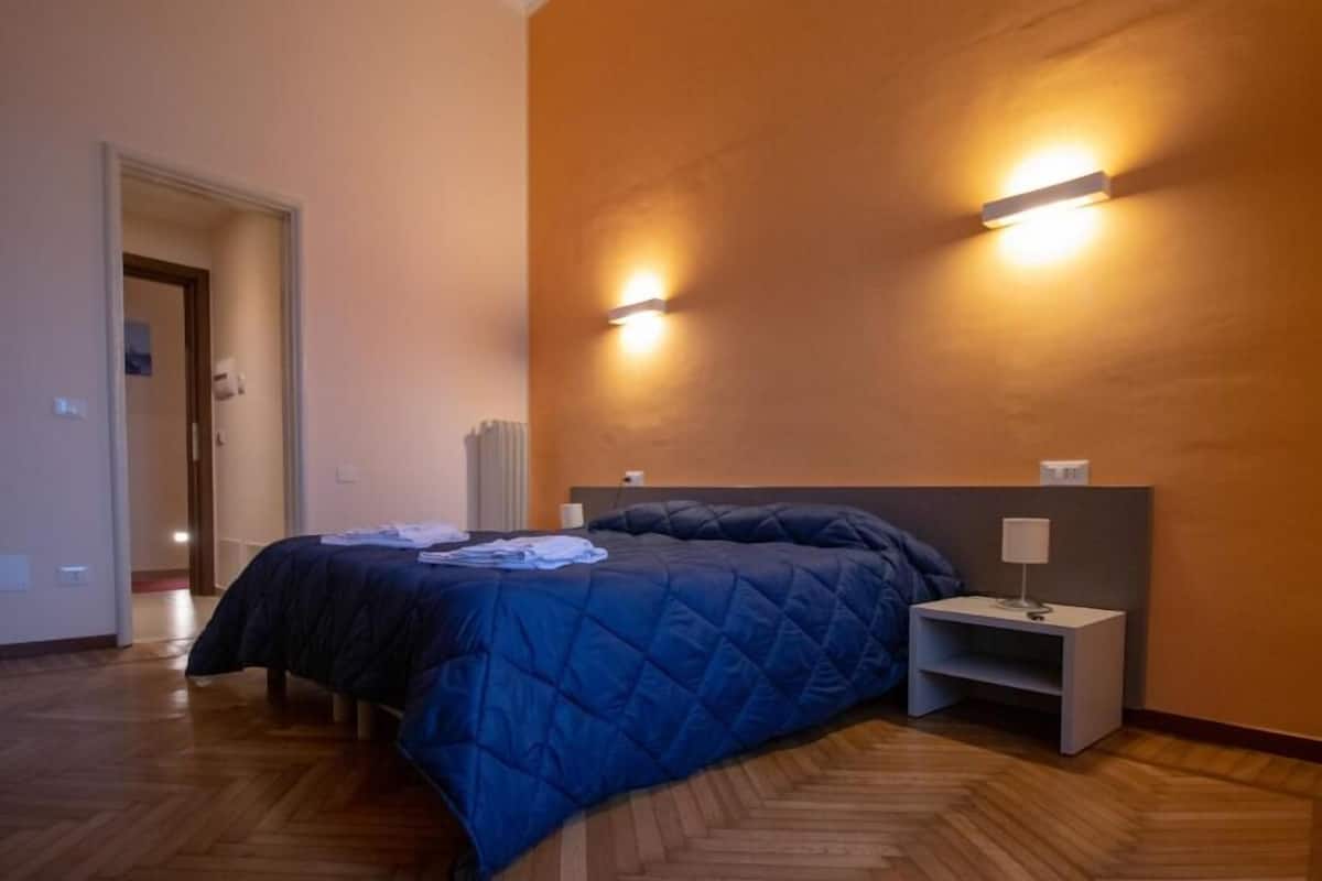 A bedroom with a bed, a nightstand, and two wall-mounted lights.