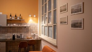 A kitchen with a bar area, a window with blinds, and several framed pictures on the wall. - Teatro sullo Stretto (Messina)