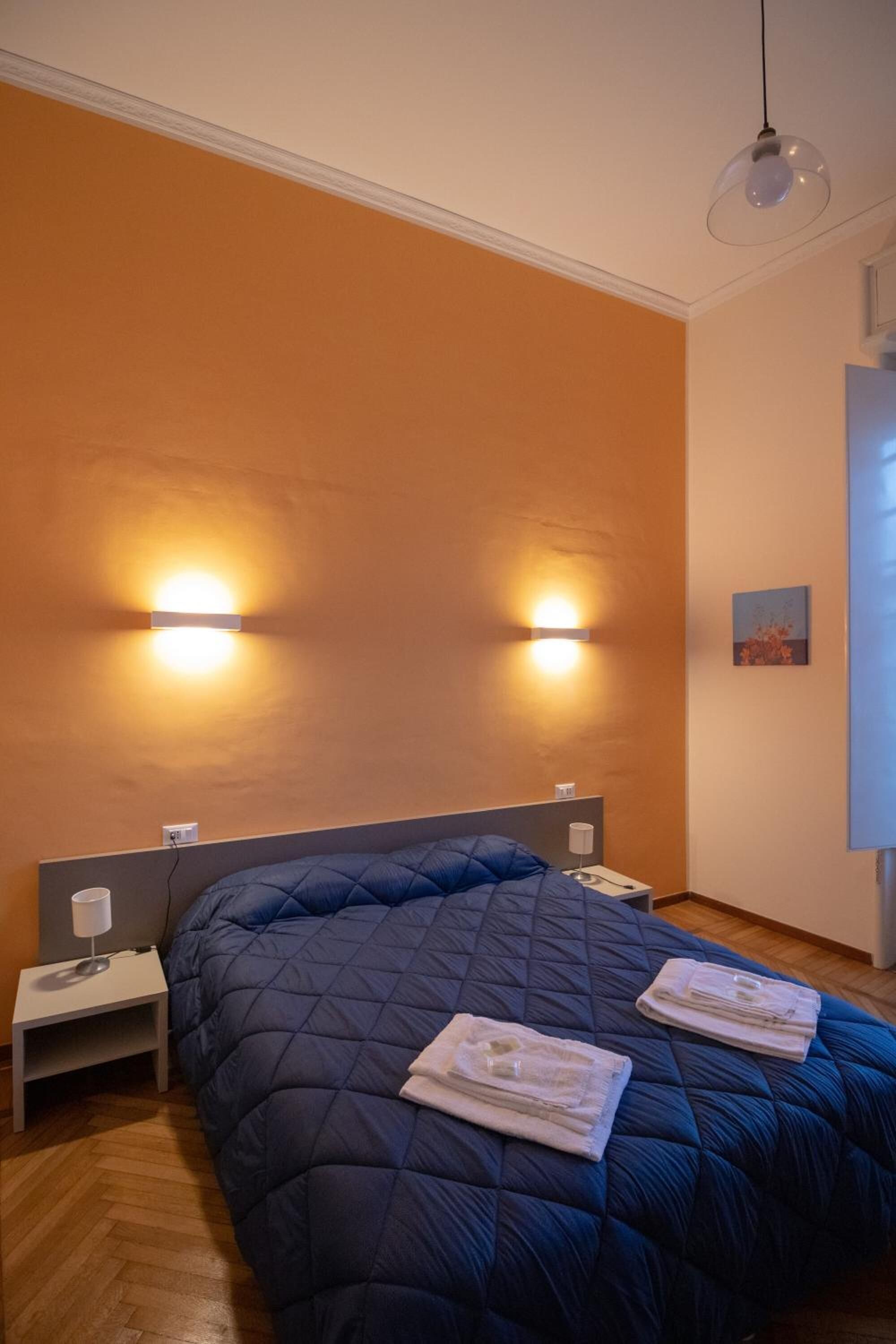 Ein Schlafzimmer mit einem großen Bett, zwei Nachttischlampen und einer Wandleuchte.