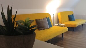 A modern living room with a yellow sofa set, a small round table, and a potted plant. - Apartment Seeadlerhorst Oberhof Boltenhagen (Oberhof)
