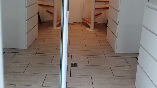 A spiral staircase in a room with white cabinets and a tiled floor. - Apartment Seeadlerhorst Oberhof Boltenhagen (Oberhof)