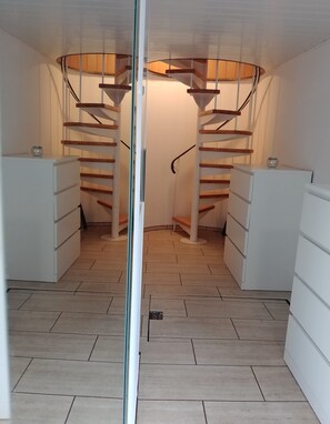 A spiral staircase in a room with white cabinets and a tiled floor. - Apartment Seeadlerhorst Oberhof Boltenhagen (Oberhof)