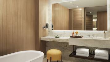A modern bathroom with a marble vanity, a freestanding bathtub, and a wooden vanity cabinet.