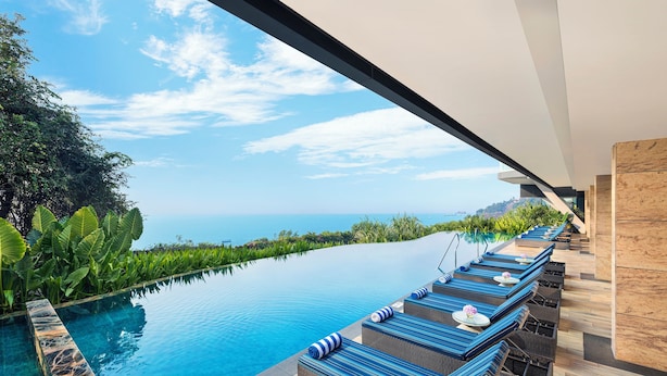 A poolside area with lounge chairs and a view of the ocean. - Taj Cidade de Goa Horizon, Goa (Panaji)
