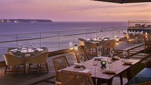 An outdoor dining area with tables and chairs, overlooking the sea. - Taj Cidade de Goa Horizon, Goa (Panaji)