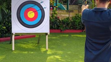A person aiming an arrow at a target with concentric circles.