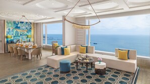 A spacious room with a large window overlooking the sea, a dining area with a table set for four, and a seating area with sofas and a coffee table. - Taj Cidade de Goa Horizon, Goa (Panaji)