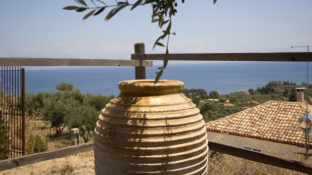 A large ceramic pot with a rustic fence in the foreground, overlooking a coastal landscape with olive trees and a clear blue sky. - DIMITRA (no 4)... vacation villa in Koroni of Messinia with sea view!!! (Koroni)