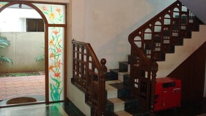 A staircase with a wooden handrail and a red object on the landing. - Lloyds Guest House , Krishna street , T. Nagar (Chennai)