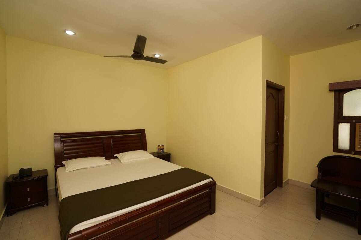 A bedroom with a wooden bed, a nightstand, a ceiling fan, and a door.