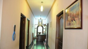 A hotel hallway with a reception desk, a framed painting, and a tennis racket on the wall. - Lloyds Guest House , Krishna street , T. Nagar (Chennai)
