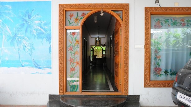 A building entrance with a wooden door and glass panels, a tiled floor, and a parked car. - Lloyds Guest House , Krishna street , T. Nagar (Chennai)