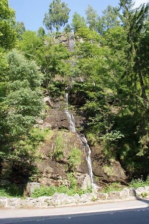 A waterfall cascading down a rocky cliff surrounded by dense green foliage.