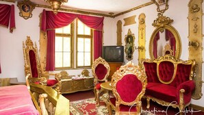 Una habitación ricamente decorada con muebles ornamentales, un candelabro y un espejo grande.