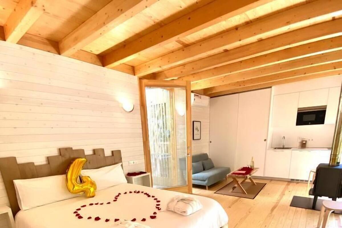 Une chambre avec un cadre en bois, comprenant un lit, un petit coin salon et une kitchenette.