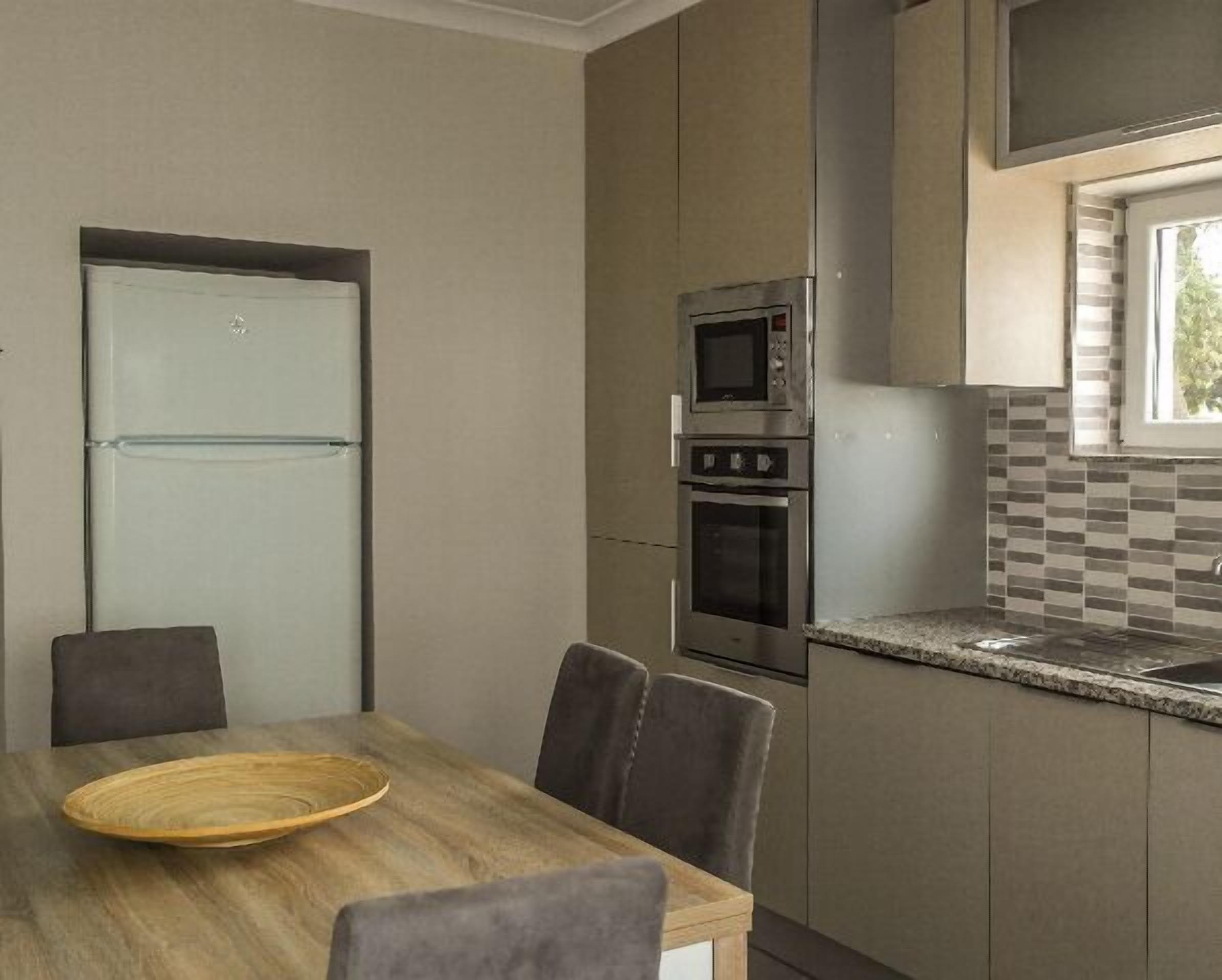 Uma cozinha compacta com geladeira, forno, micro-ondas e painel de fundo xadrez.
