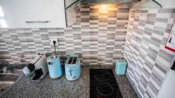 A kitchen with a checkered backsplash, a built-in stove, and two blue toasters.