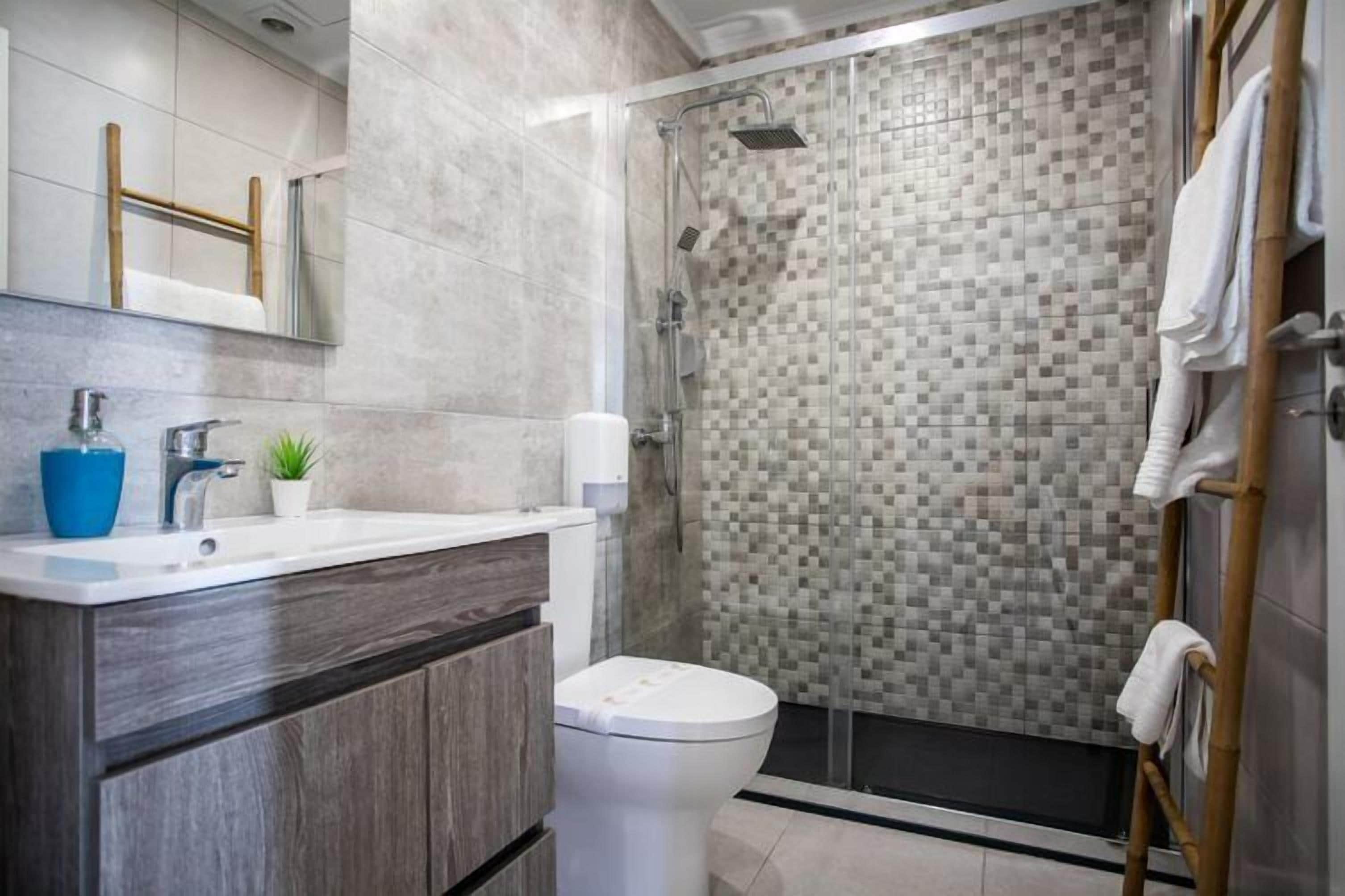 A modern bathroom with a shower, toilet, and sink.