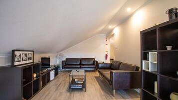 A modern living room with a dark leather sofa, a coffee table, and built-in shelving.