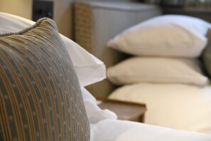 A bed with white bedding and a striped pillow.