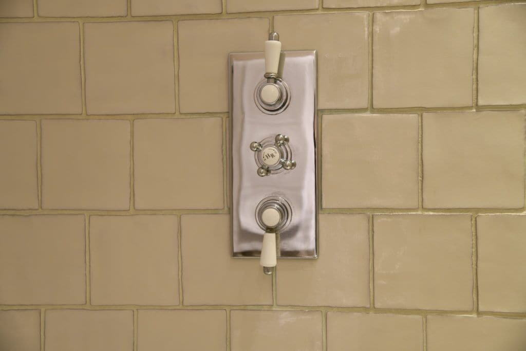A wall-mounted light switch with a white handle and a circular design on the plate.