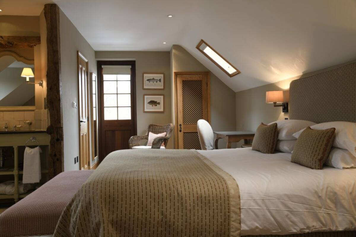A bedroom with a large bed, a chair, a desk, and a bathroom area.