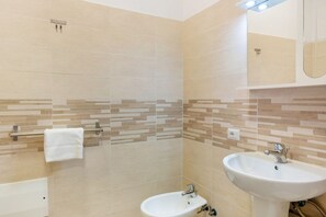 A bathroom with beige tiles, a white sink, a mirror, and a towel rack.
