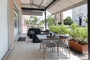 An outdoor patio with tables and chairs, a covered area, and a view of a building with a sign.