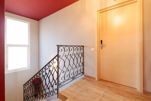 Eine Treppe mit schmiedeeisernem Geländer, einer Holztür und einem Fenster mit Rollläden.