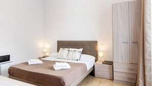 Una habitación de hotel con cama, mesitas de noche, armario y televisión.