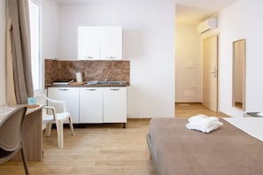 Een hotelkamer met een bed, een bureau met stoel, een kitchenette en een badkamer.
