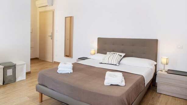 Ein Hotelzimmer mit Bett, Nachttischen, einem Spiegel und einer Tür.