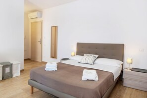 A hotel room with a bed, bedside tables, a mirror, and a door.