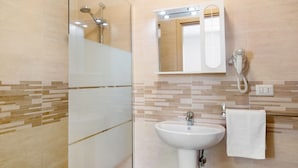 A bathroom with a glass shower enclosure, a sink with a mirror, and a towel rack.