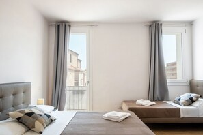 Een hotelkamer met een bed, een eenpersoonsbed, een nachtkastje en een raam met gordijnen.