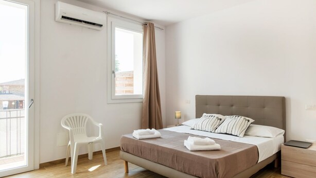 Une chambre à coucher comprenant un lit, une chaise, une table de chevet et un appareil de climatisation.